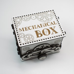 May include: A white wooden mechanical box with intricate gear designs and the words "MECHANICAL BOX" engraved on the lid. The box features a complex gear mechanism on the side, showcasing a steampunk aesthetic.