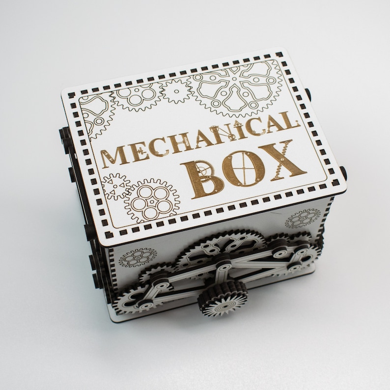 May include: A white wooden mechanical box with intricate gear designs and the words "MECHANICAL BOX" engraved on the lid. The box features a complex gear mechanism on the side, showcasing a steampunk aesthetic.