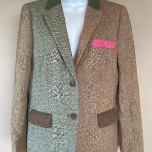 Könnte beinhalten: Ein Blazer mit geteiltem Design, bei dem eine Seite ein salbeigrünes Fischgrätenmuster und die andere einen beigen Tweedstoff aufweist. Er verfügt über einen dunkelgrünen Kragen, zwei dunkle Knöpfe, zwei dunkelbraune Pattentaschen und ein pinkes Einstecktuch.