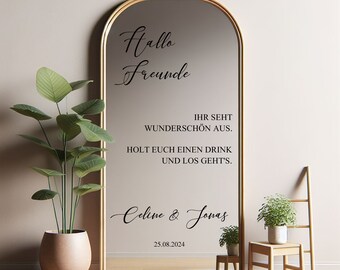 Pode incluir: Um espelho arqueado dourado com um decalque de vinil preto que diz "Hallo Freunde" e inclui o texto "IHR SEHT WUNDERSCHÖN AUS. HOLT EUCH EINEN DRINK UND LOS GEHT'S." e "Celine & Jonas 25.08.2024".