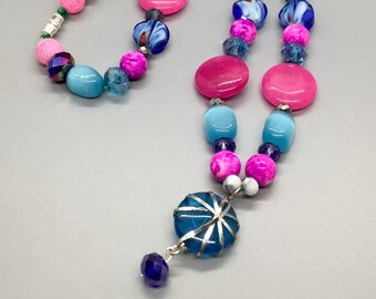 Collar de cuentas de cristal azul y rosa con colgante de cristal azul envuelto en plata con un golpe colgante de cristal de tanzanita