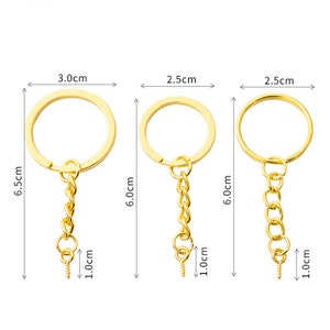 May include: Three gold keychains with different sized rings and chains. The rings measure 3.0 cm, 2.5 cm, and 2.5 cm in diameter. The chains are 6.0 cm long and have a 1.0 cm screw clasp.