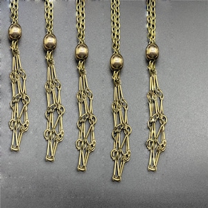 May include: Five gold-toned chains with a round bead at the top and a decorative chain tassel at the bottom.