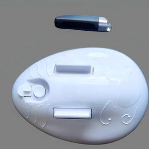 May include: A white, egg-shaped plastic device featuring two rectangular white tabs, a small circular button, and a sliding switch. Positioned above the main unit is a separate, small, dark gray, elongated component with a metallic silver end.