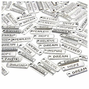 Könnte beinhalten: Eine Sammlung silberfarbener Metall-Anhänger mit inspirierenden Wörtern wie "Hope", "Dream", "Faith", "Believe", "Inspire", "Fearless", "Best", "Friends" und "Blessed".
