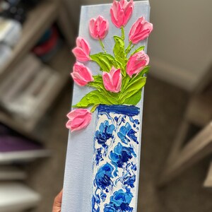 May include: A rectangular canvas painting featuring a vase of pink tulips. The vase is blue and white with a floral pattern. The tulips have green leaves and are painted with a textured, raised effect, creating a 3D appearance.