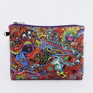 May include: A rectangular zippered pouch with a vibrant, psychedelic design. The artwork features a chaotic mix of colorful, cartoonish faces, eyes, and abstract shapes in red, orange, yellow, blue, and green. The zipper is silver, and the trim is purple.