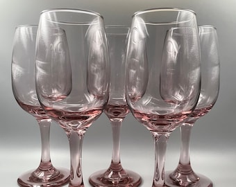 Op de afbeelding: Set van zes heldere wijnglazen met een licht roze tint. De glazen hebben een klassieke vorm met een ronde kom en een lange steel.