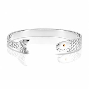May include: A silver-colored cuff bracelet with a fish design. The bracelet features a fish tail on one end and a fish head with a gold-colored eye on the other. The fish scales are detailed, and the bracelet is reflective.