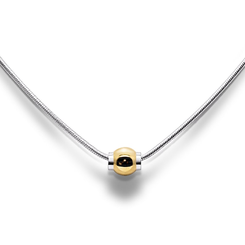 May include: A silver chain necklace with a single gold bead pendant.