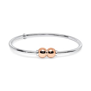 May include: A silver bangle bracelet with two rose gold beads. The bracelet is open and has a hinged clasp.