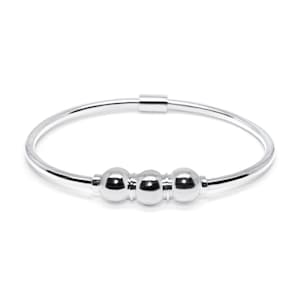 May include: A silver bangle bracelet with three round beads. The beads are smooth and shiny.