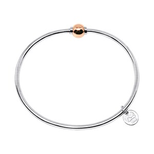 May include: A silver bangle bracelet with a rose gold ball charm and a small silver charm with the word "Elle" engraved on it.