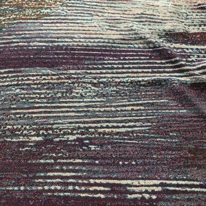 May include: A close-up of a textured fabric with a striped pattern in shades of brown, green, and white.