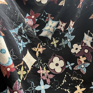May include: Black fabric with a repeating pattern of colorful flowers and the Louis Vuitton logo.