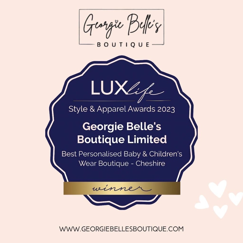 May include: A navy blue award badge with white text, featuring the words "LUXlife Style & Apparel Awards 2023" and "Georgie Belle's Boutique Limited". The badge is for "Best Personalised Baby & Children's Wear Boutique - Cheshire". The word "winner" is also visible.