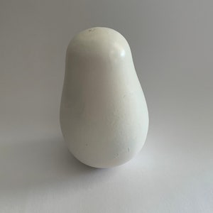 Puede incluir: Una muñeca rusa de anidación de cerámica blanca, también conocida como muñeca matryoshka, con forma de pera. La muñeca es lisa y tiene un acabado brillante.