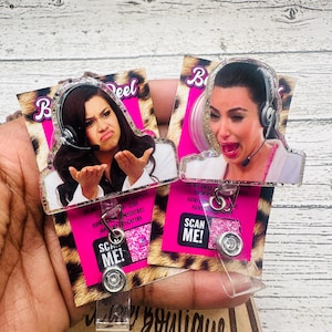 May include: Two retractable badge reels featuring images of women wearing headsets with expressive faces. The reels have a pink background with leopard print and the text "SCAN ME!". The word "Boutique" is visible at the bottom.