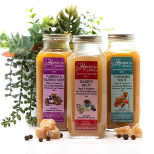 May include: Three glass bottles of Hartini's Jamu, a Javanese traditional elixir. The labels read "Turmeric & Tamarind Shot", "Ginger Shot", and "Turmeric Shot". Each bottle contains 16 fl oz of fresh pressed juice. The bottles are displayed with ginger and peppercorns.