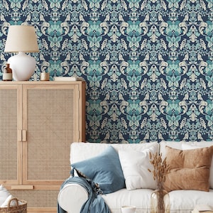 May include: A navy blue wallpaper with a repeating floral damask pattern in shades of teal and cream. The wallpaper is the backdrop for a living room scene with a white sofa, blue pillows, and a wooden cabinet.