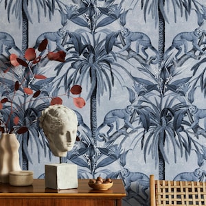 Może przedstawiać: Pokój z niebiesko-białą tapetą z powtarzającym się wzorem małp, palm i tropikalnych liści. Drewniana komoda prezentuje biały gipsowy popiersie, wazony i miskę z orzechami. Czerwonobrązowe gałęzie dodają koloru.