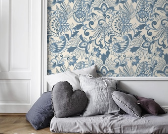 May include: A bed with a gray duvet and several pillows, including a heart-shaped pillow. The wall behind the bed is covered in a blue and white paisley patterned wallpaper.