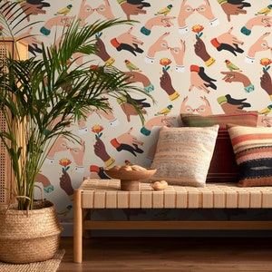 以下が含まれることがあります： カラフルな手、鳥、花が繰り返し描かれたベージュの壁紙。壁紙は、籐製の座面と2つのクッションが付いた薄い茶色の木製のベンチの後ろにある。クッションの1つはベージュでストライプ模様、もう1つはマルチカラーのストライプ模様である。