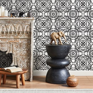 May include: A decorative interior scene featuring a carved wooden fireplace, a small wooden stool with a book, and a black, stacked side table. The background is a black and white patterned wallpaper, and the scene is accented with small decorative objects.