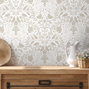 Puede incluir: Papel pintado floral en tonos neutros con un patrón repetido de flores, hojas y mariposas estilizadas. Un sombrero de paja, una jarra blanca y una cesta de mimbre con flores blancas sobre una superficie de madera.