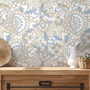 Pode incluir: Um design de papel de parede floral em branco, azul claro e bege. Um chapéu de palha, um jarro branco e uma pequena cesta de flores brancas estão sobre uma superfície de madeira. O papel de parede apresenta um padrão repetido de flores e folhas estilizadas.