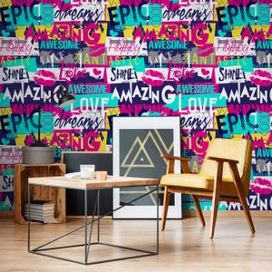 May include: A room interior with a yellow chair, a wooden coffee table, and a framed print with a geometric design. The wall is covered in a colorful wallpaper with the words "EPIC", "AMAZING", "LOVE", "DREAMS", "HAPPY", "AWESOME", "FANTASTIC", and "SHINE" repeated in a bold, graphic style.