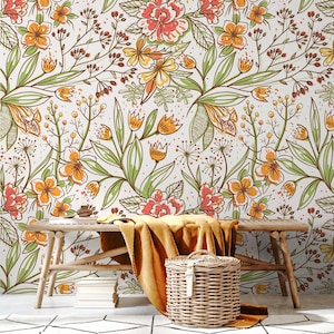 May include: Floral wallpaper with orange, yellow, and red flowers, green leaves, and brown stems on a white background. A wooden bench, a yellow blanket, and a wicker basket are in front of the wallpaper.