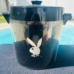 Puede incluir: Una taza de cerámica blanca con asa negra y el texto "But First, Coffee" en negrita negra. La taza se encuentra sobre un fondo neutro, resaltando su diseño sencillo.