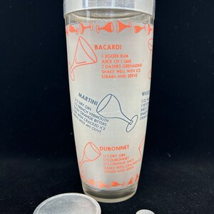 Puede incluir: Un coctelera de plata con un inserto de vidrio que presenta recetas de c&oacute;cteles Bacardi, Martini y Dubonnet. La coctelera tiene una tapa de plata y una base de plata.