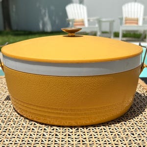 May include: A yellow and white vintage cooler with a lid and two handles. The cooler has a textured surface and a white band around the middle.