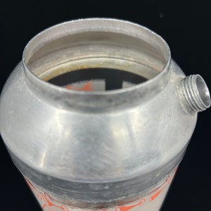 Puede incluir: Una coctelera de plata con una banda negra y una etiqueta blanca con texto rojo. La etiqueta dice "Bacardi Rum 1 jigger de Bacardi Rum 1 jigger de jugo de lima 2 pizcas de granadina Agitar bien Colar y servir"