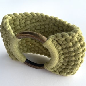 May include: A green crocheted bracelet with a brass ring closure.