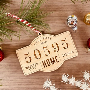 May include: A wooden Christmas ornament shaped like a sign with the text "Christmas 2022", "50595", "Webster City", "Home", and "Iowa".