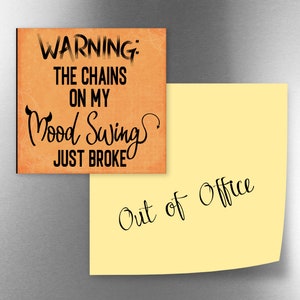 May include: A warning sign on a refrigerator magnet with the text "WARNING: THE CHAINS ON MY MOOD SWING JUST BROKE" and a yellow sticky note with the text "Out of Office".