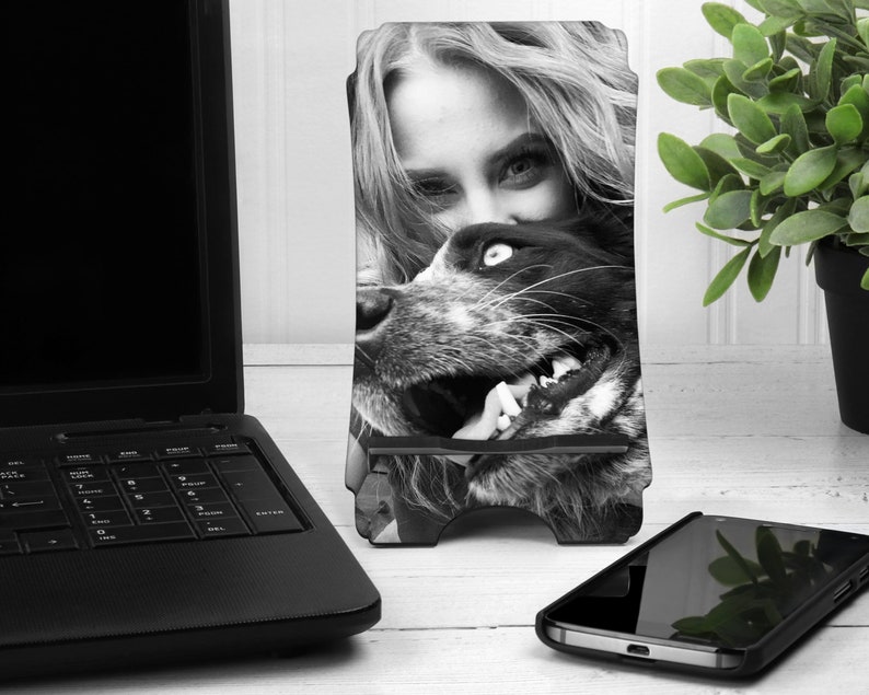 May include: Black and white photo of a woman and a dog. The woman is leaning down and the dog is looking up at her. The photo is printed on a phone stand.