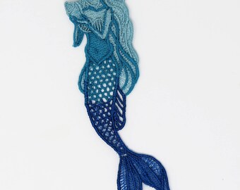 May include: A blue and teal embroidered mermaid with a long flowing tail. The mermaid is holding a seashell in her hands.
