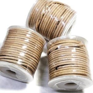 May include: Three spools of beige leather cord, each wrapped in clear plastic and ready for crafting projects.