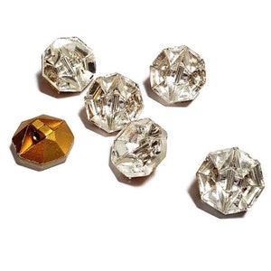 May include: Five clear glass buttons with a faceted design, and one gold button with a faceted design.