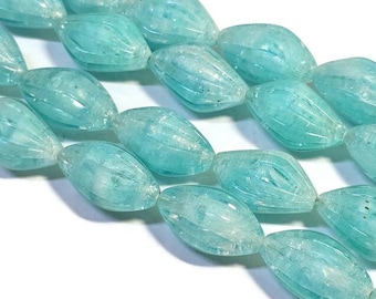 May include: A strand of light blue glass beads with a faceted, oval shape. The beads have a translucent, slightly cloudy appearance.