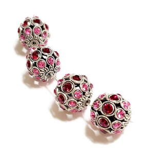 May include: Four silver and pink rhinestone round beads. The beads are strung together on a silver wire.