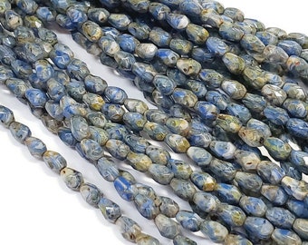Può includere: Una collana di perline di vetro blu e bianco con una forma allungata sfaccettata. Le perline hanno un aspetto marmorizzato e screziato.