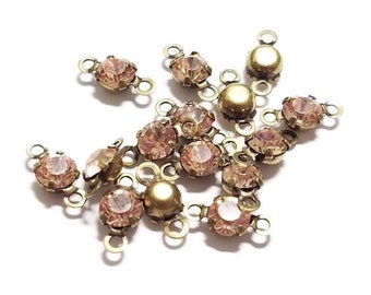 May include: A group of antique gold-toned metal connector charms with pink rhinestones. Each charm has two loops for attaching to jewelry.