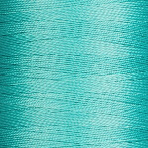 May include: A spool of teal thread. The thread is wound tightly and has a smooth, shiny finish.