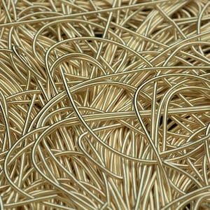 May include: A close-up of a pile of gold-coloured wire, creating a tangled and textured pattern.