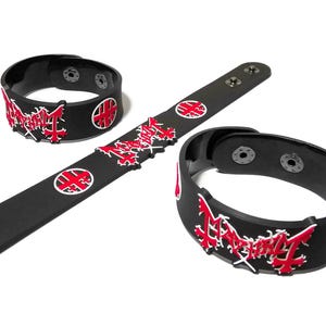 May include: Three black silicone wristbands featuring a raised red and white logo design. Each band includes a metal snap button closure. The design displays a stylized red text graphic and a circular red and white emblem on a matte black surface.